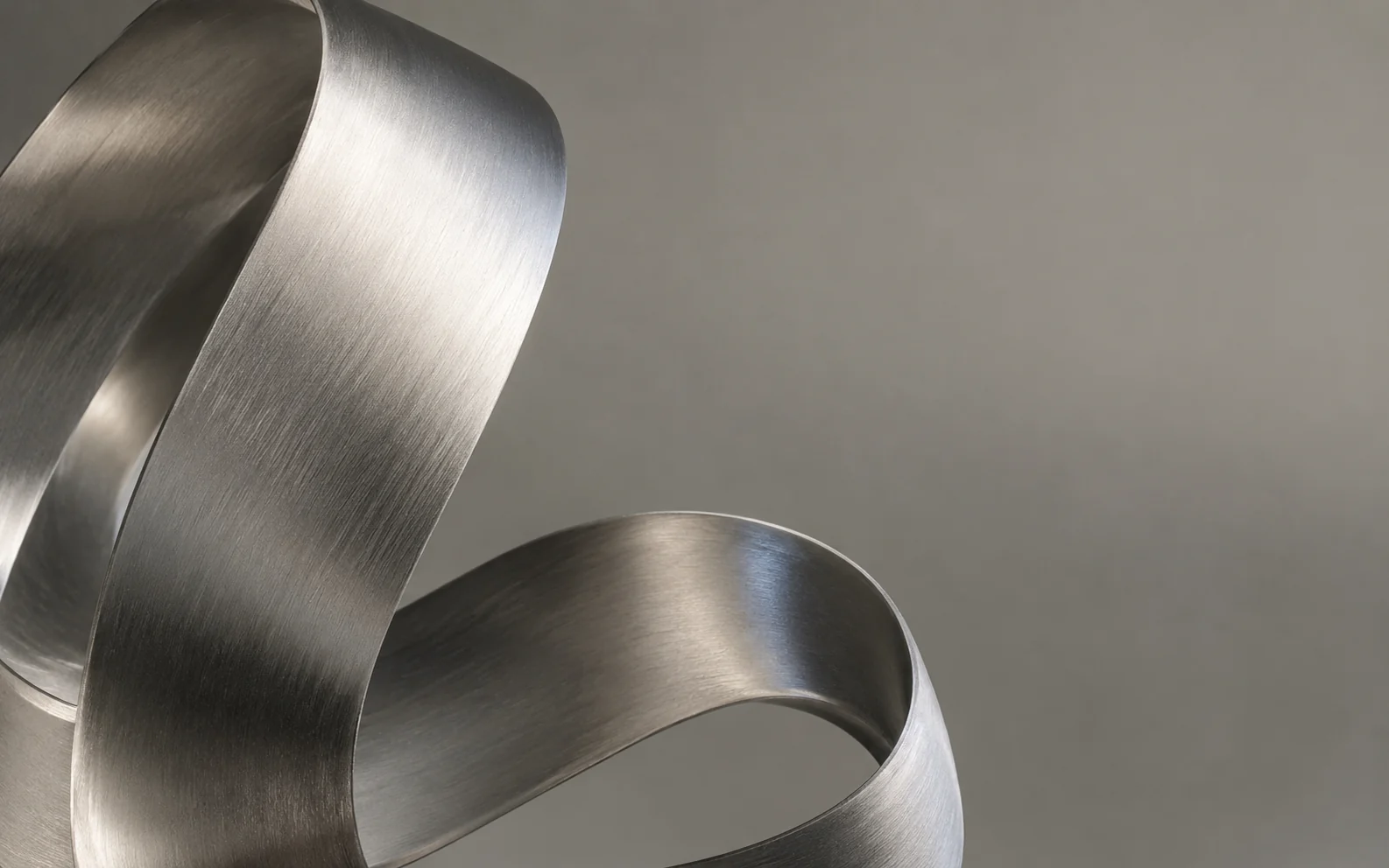 A continuous ribbon of brushed metal folding through soft light